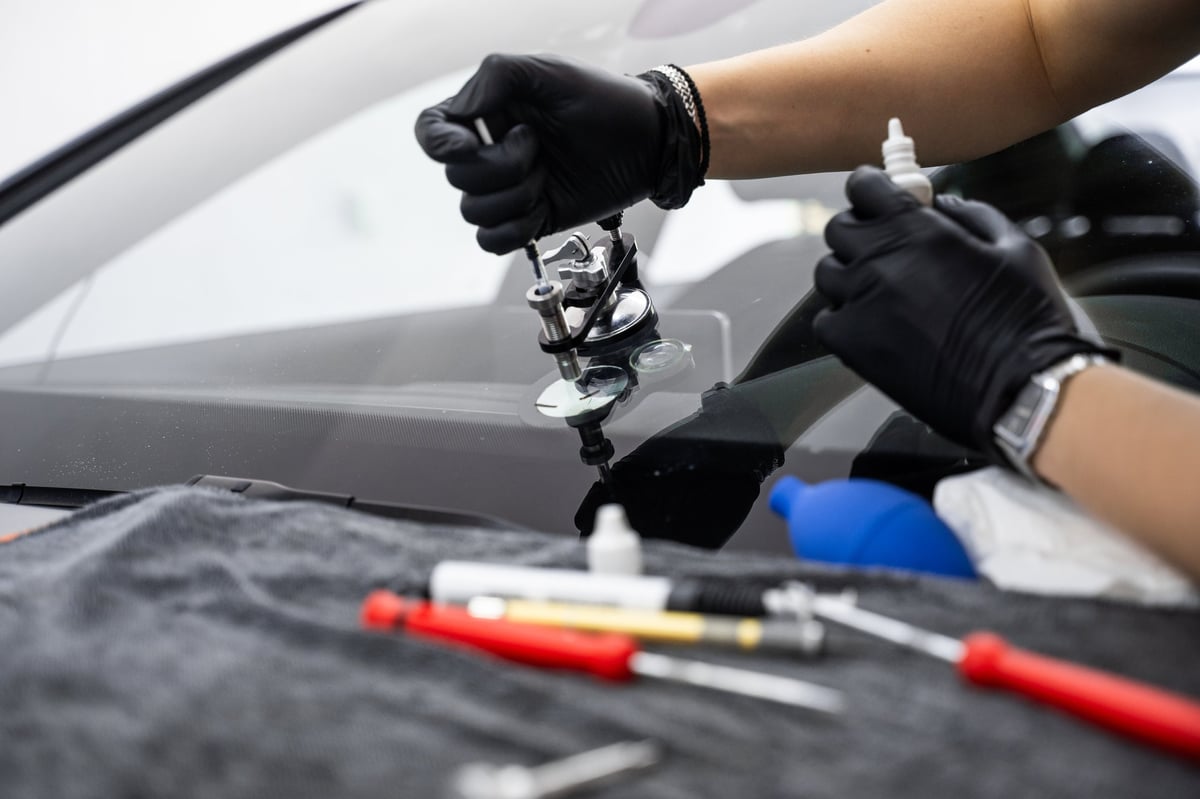 Technician injecting resin into a bullseye chip in a windshield to restore structural clarity